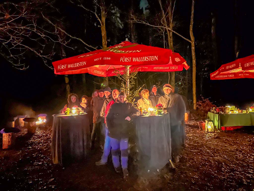 Menschen stehen unter einem roten Sonnenschirm im Wald bei Nacht