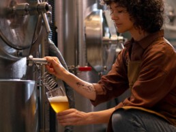 Eine Frau füllt Bier in ein Glas in einer Brauerei