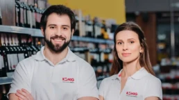 Ein Mann und eine Frau in wei&szlig;en Shirts stehen vor einem Getr&auml;nkeregal